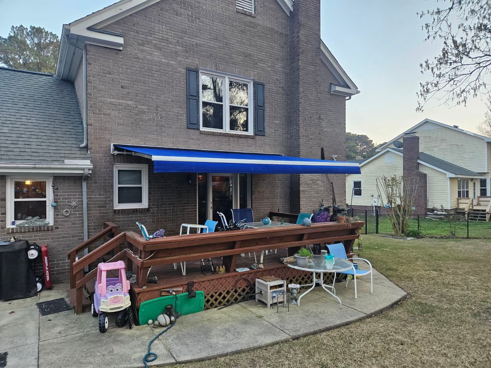 Blue retractable awning brick home with deck