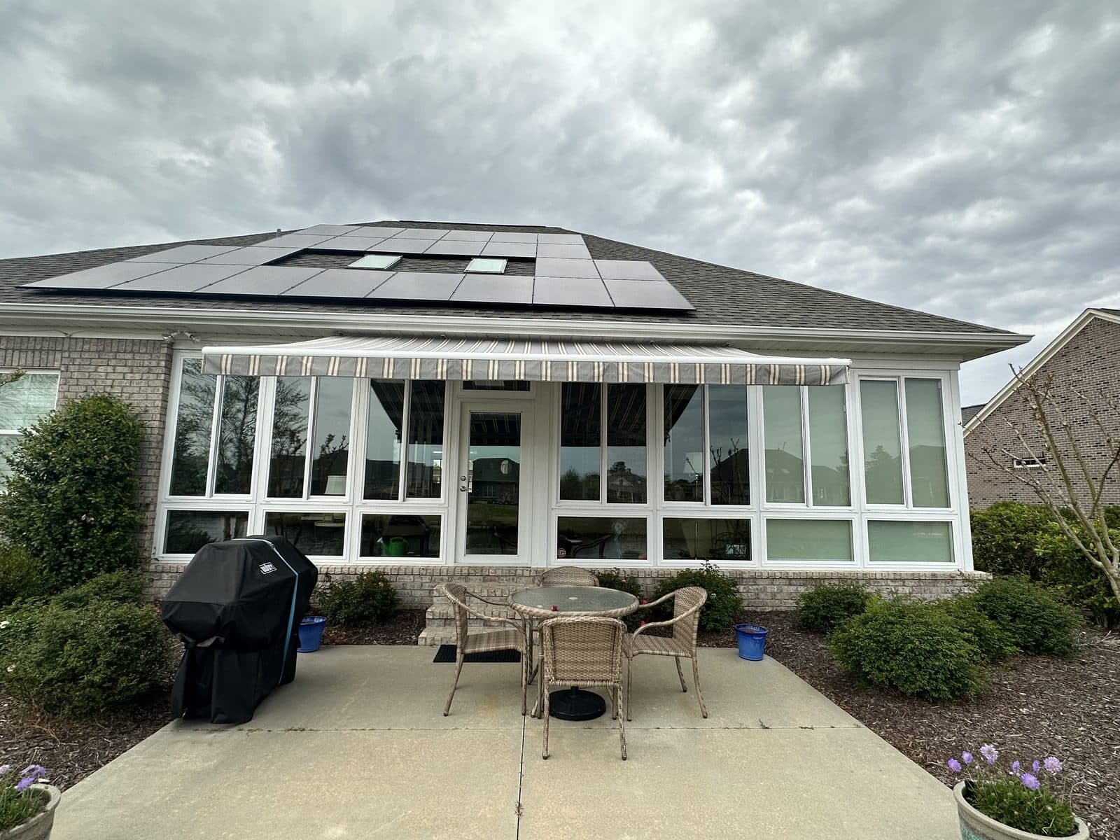 Striped retractable awning over a sunroom entrance
