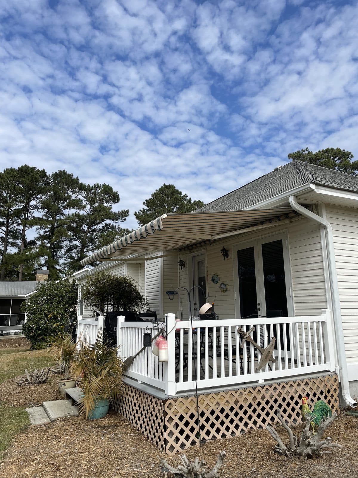 Striped retractable awning extended over a white home porch